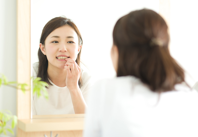鏡で歯をチェックする女性